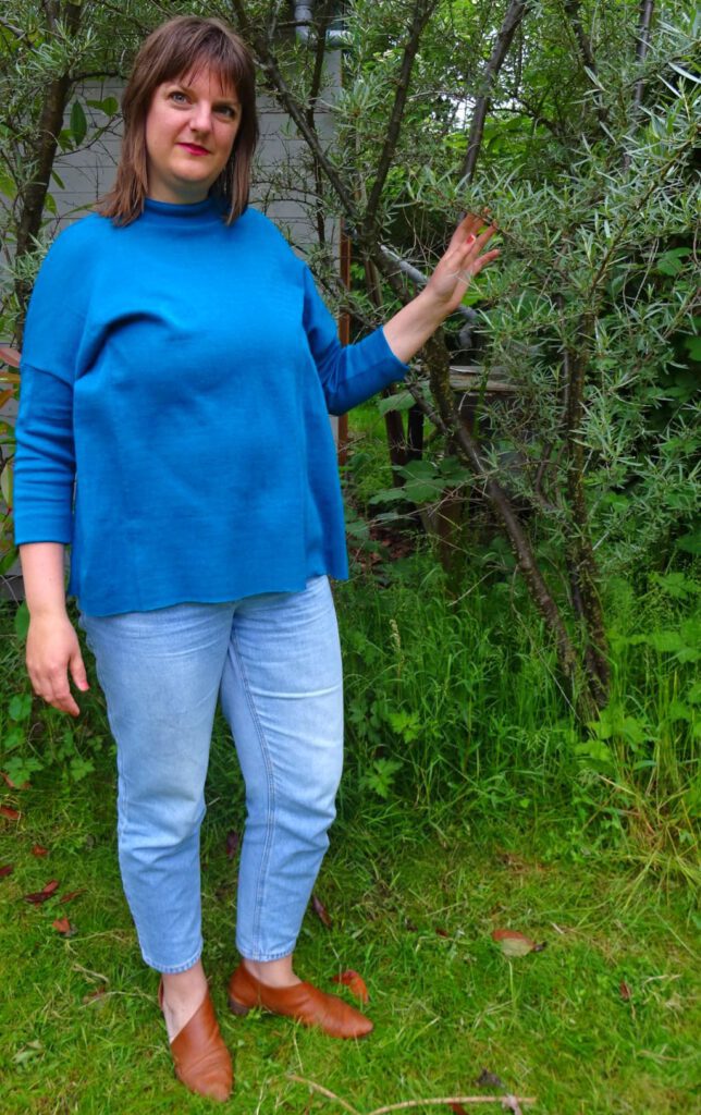 Tine Sews posiert in einem blauen Monroe Turtleneck