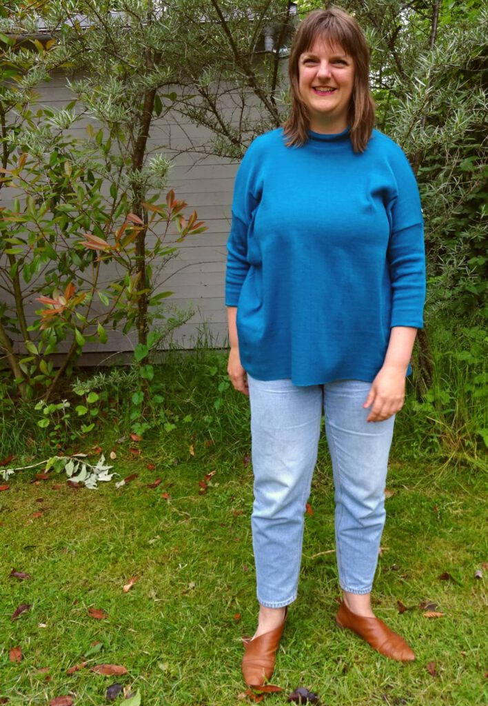 Tine Sews posiert in einem blauen Monroe Turtleneck